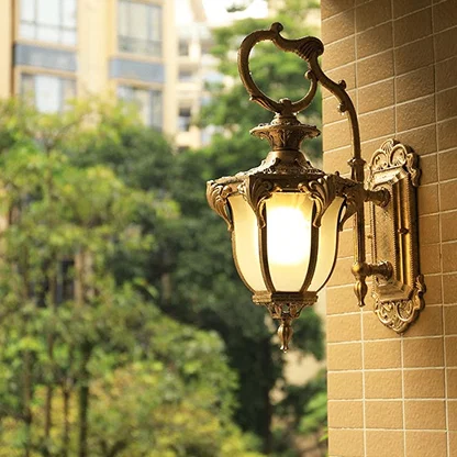 Golden antique outdoor wall light enhancing the charm of an outdoor garden area with warm ambient glow.