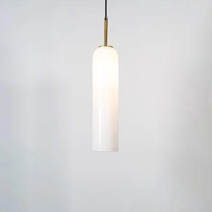 A tall cylindrical pendant light with the light on glowing warmly through the glass shade against a clean white background for a bright contemporary look.