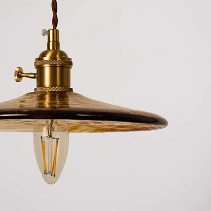 Closeup of brass metal pendant light with clear glass shade highlighting refined vintage craftsmanship.