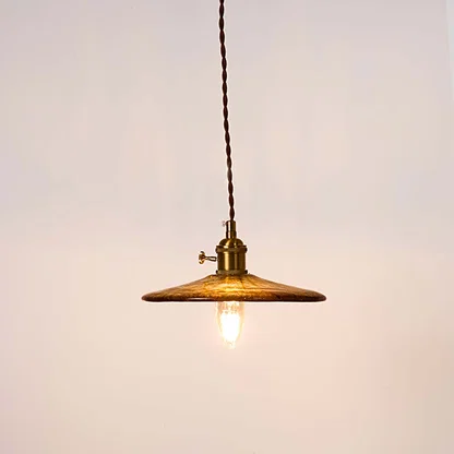 Brass metal pendant light with disc shade and exposed bulb creating warm ambient lighting indoors.