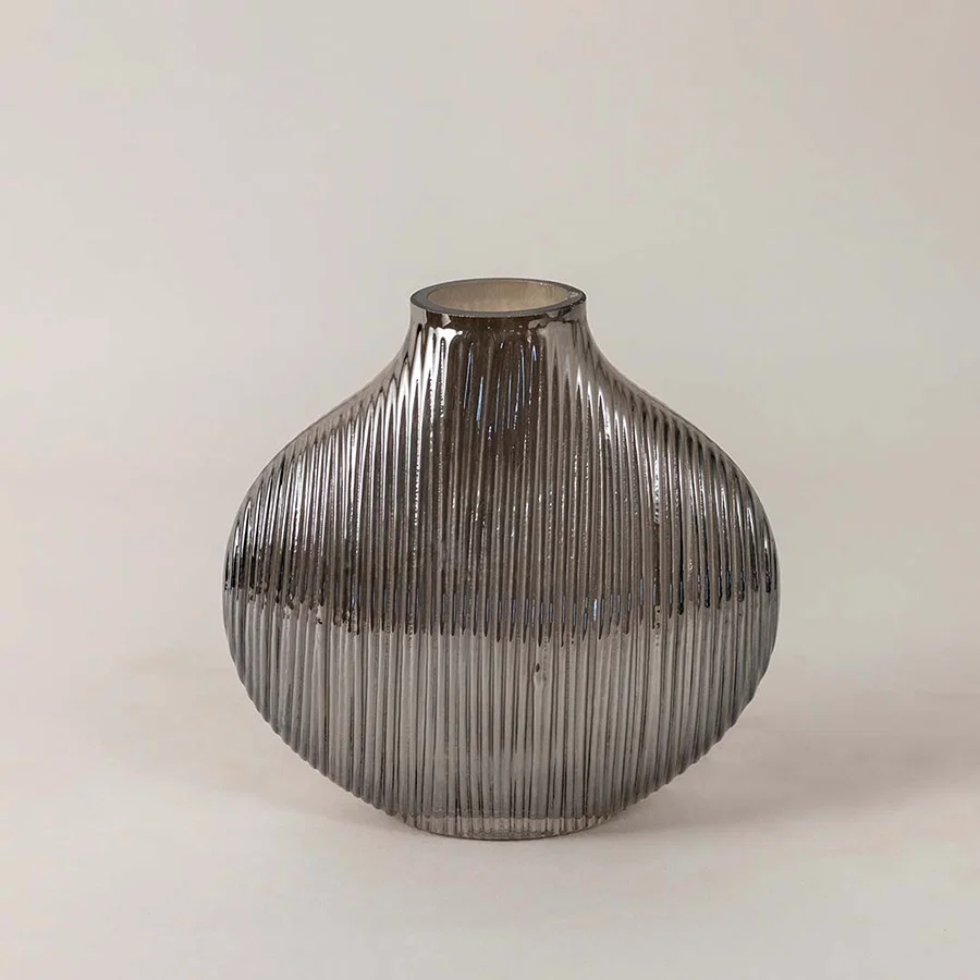 Elegant smoky glass vase with ribbed detailing and smooth round silhouette placed on a plain white surface for a minimal look.