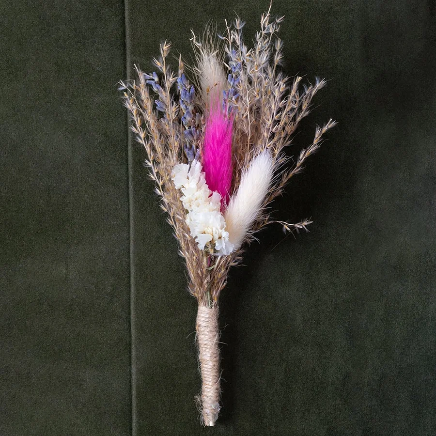 Closeup of dried flower bouquet with pink white and beige preserved stems wrapped in jute creating a rustic artificial flower arrangement.
