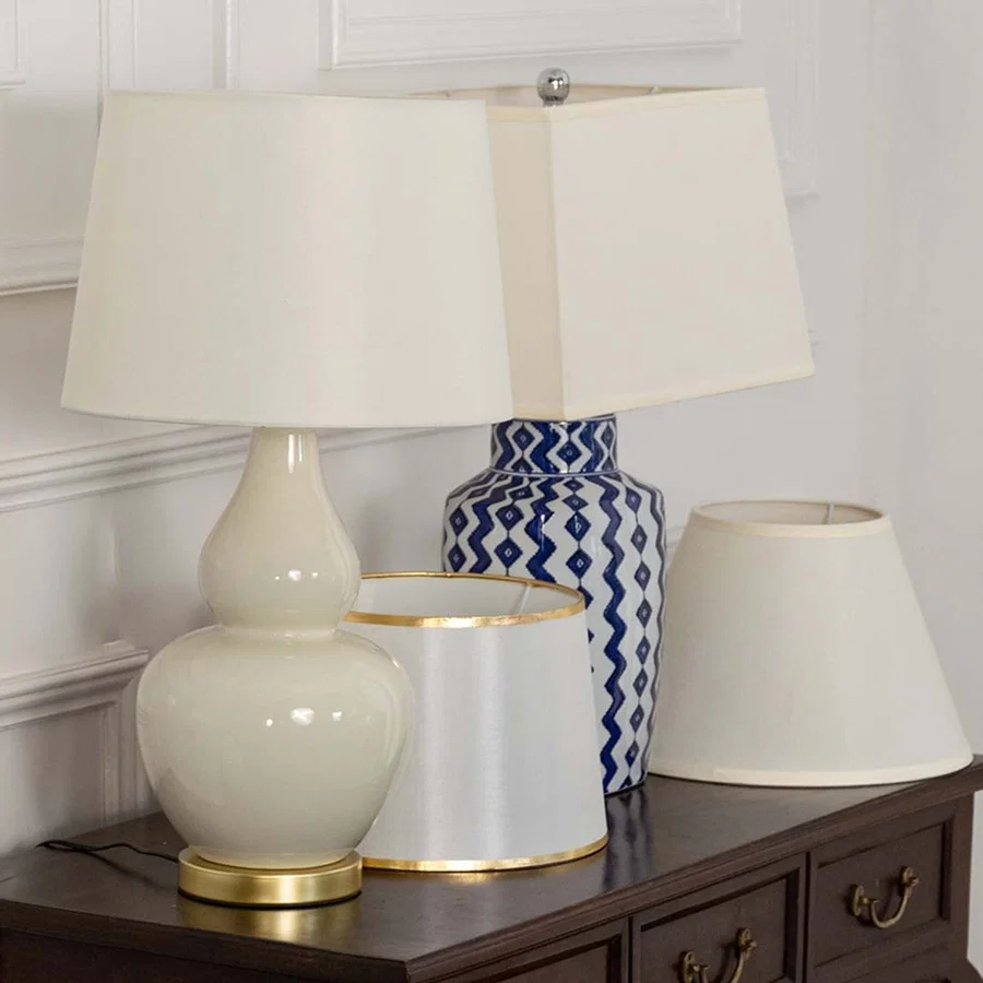 Cream shade white ceramic table lamp on wooden sideboard with light off beside decorative vases for modern cozy décor.