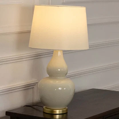 White ceramic table lamp with fabric shade displayed on a wooden console table creating elegant traditional ambient lighting.
