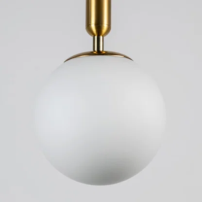 White glass globe pendant light with brass metal fixture showcasing smooth opal finish and refined modern craftsmanship.