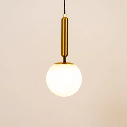 White glass globe pendant light with brass metal holder and minimalist design for elegant contemporary ceiling lighting decor.