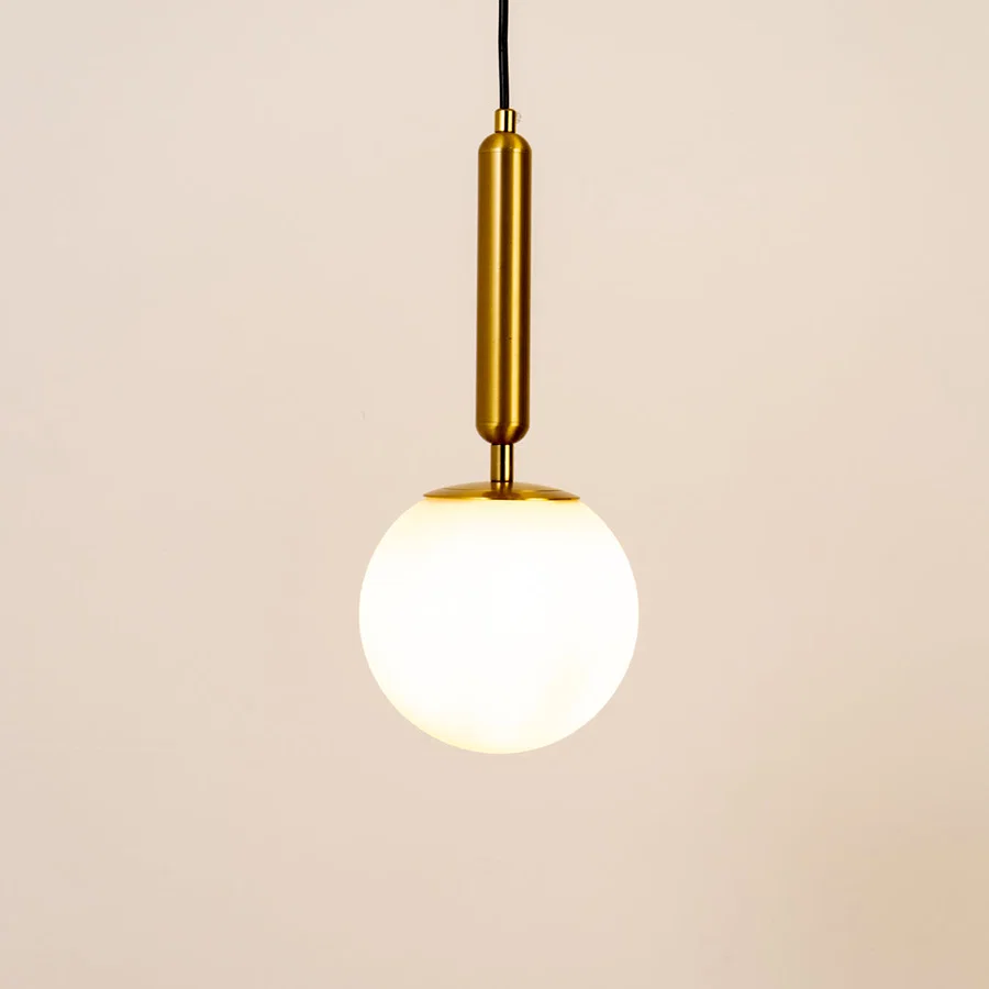 White glass globe pendant light with brass metal holder and minimalist design for elegant contemporary ceiling lighting decor.