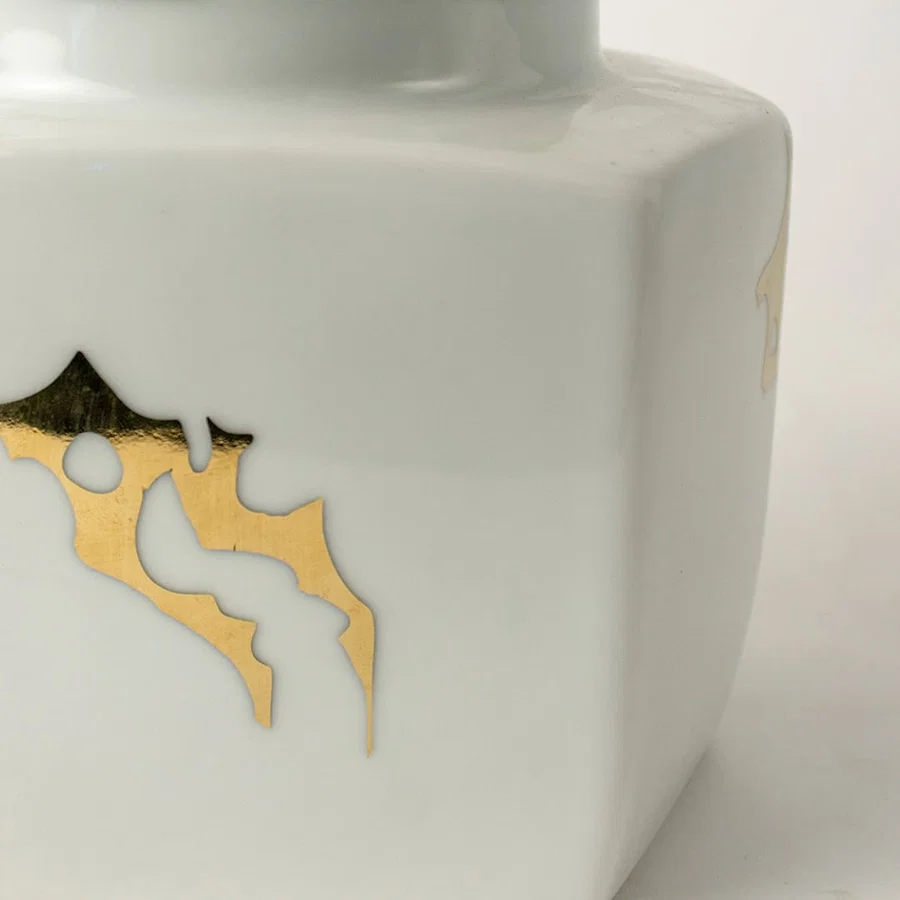 Closeup of white ceramic decorative jar with gold bee motif showcasing premium craftsmanship and elegant detailing.