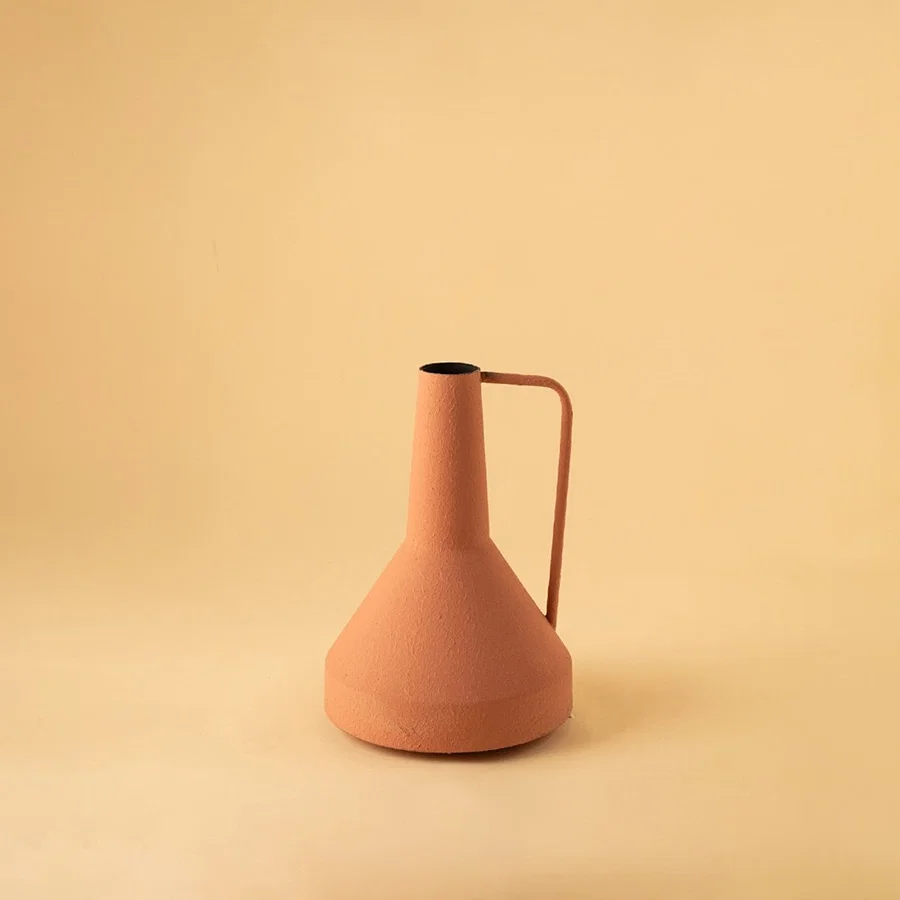 Cream colored ceramic pitcher with minimalist design and angular metal handle perfect for contemporary home decor and flower arrangements.