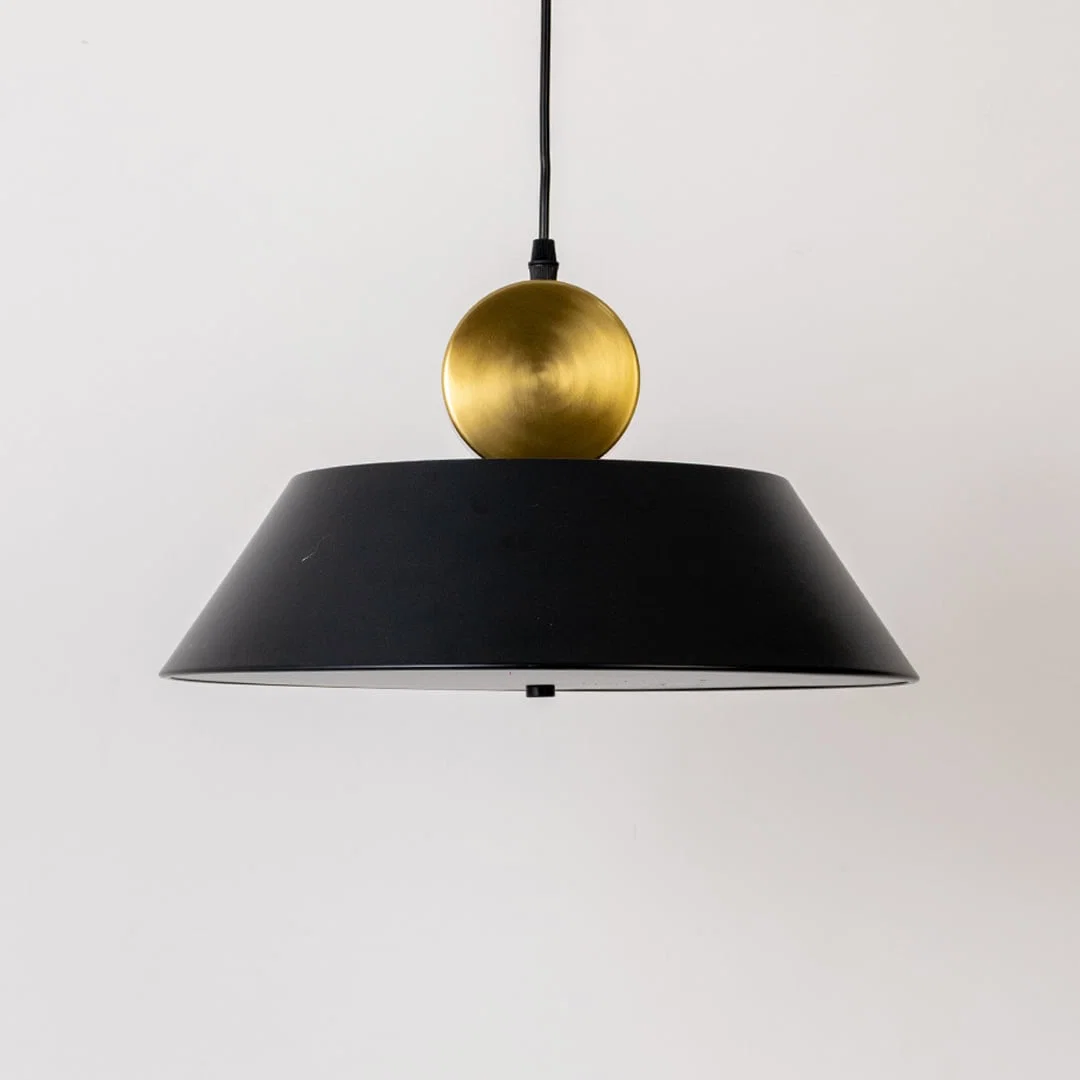 Black metal pendant light with gold sphere accent illuminated to display contemporary ceiling lighting with luxury appeal.