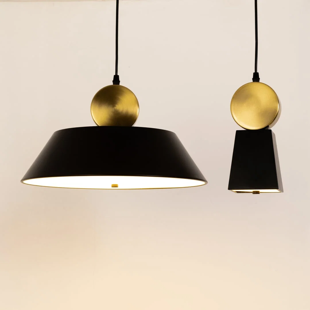 Black metal pendant lights with gold sphere accents illuminated to display elegant decorative ceiling lighting.
