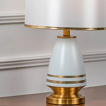White shade gold and white table lamp on wooden console table with light off and white panel wall background for modern elegant décor.