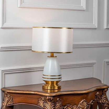 Table lamp with white shade and gold metal base placed on wooden side table ideal for bedroom living room decor styling.