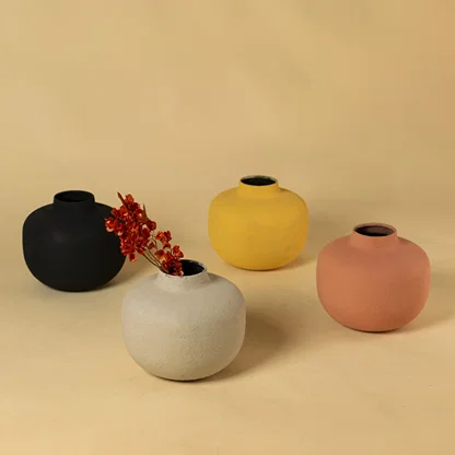Collection of four colorful matte round metal bud vases for vibrant modern home decor and artistic centerpiece arrangement.