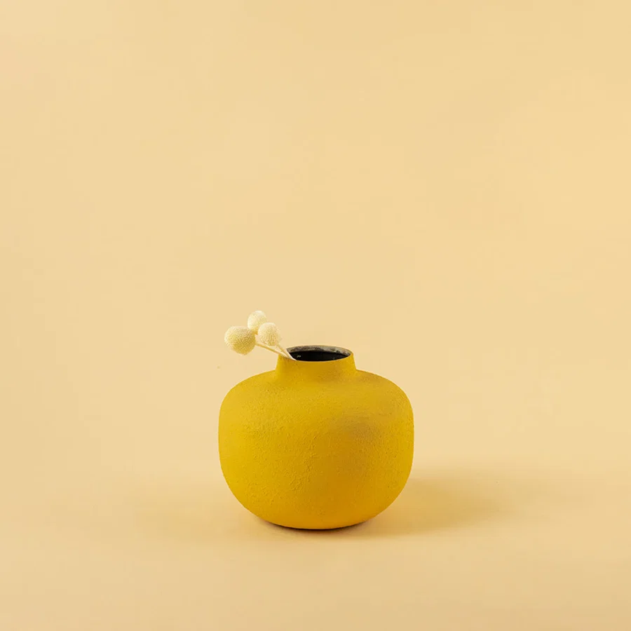 Minimalist matte yellow round metal bud vase with dried stem for modern home decor and elegant shelf accents.
