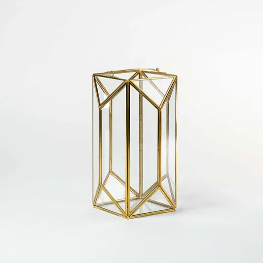 Gold metal geometric candle holder with open frame design for luxury tabletop decor styling use.