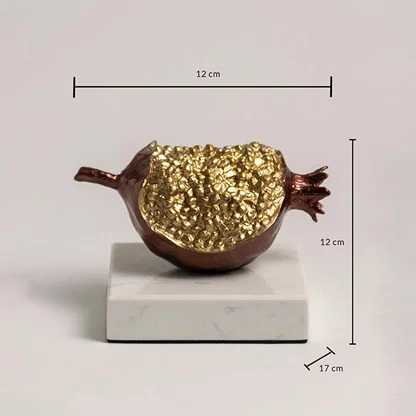 Golden pomegranate sculpture on marble base showing 12 cm height and 17 cm width dimensions.