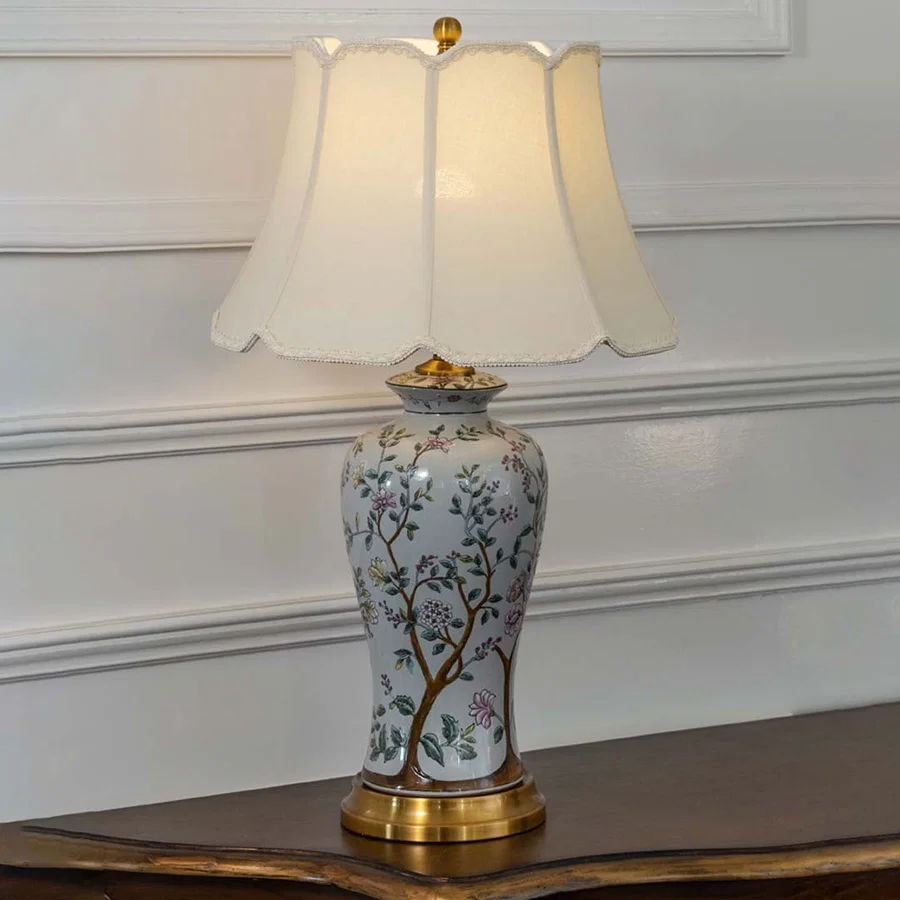 Floral ceramic table lamp with gold base and cream shade emits a warm soft light that enhances cozy and luxurious interior settings beautifully.