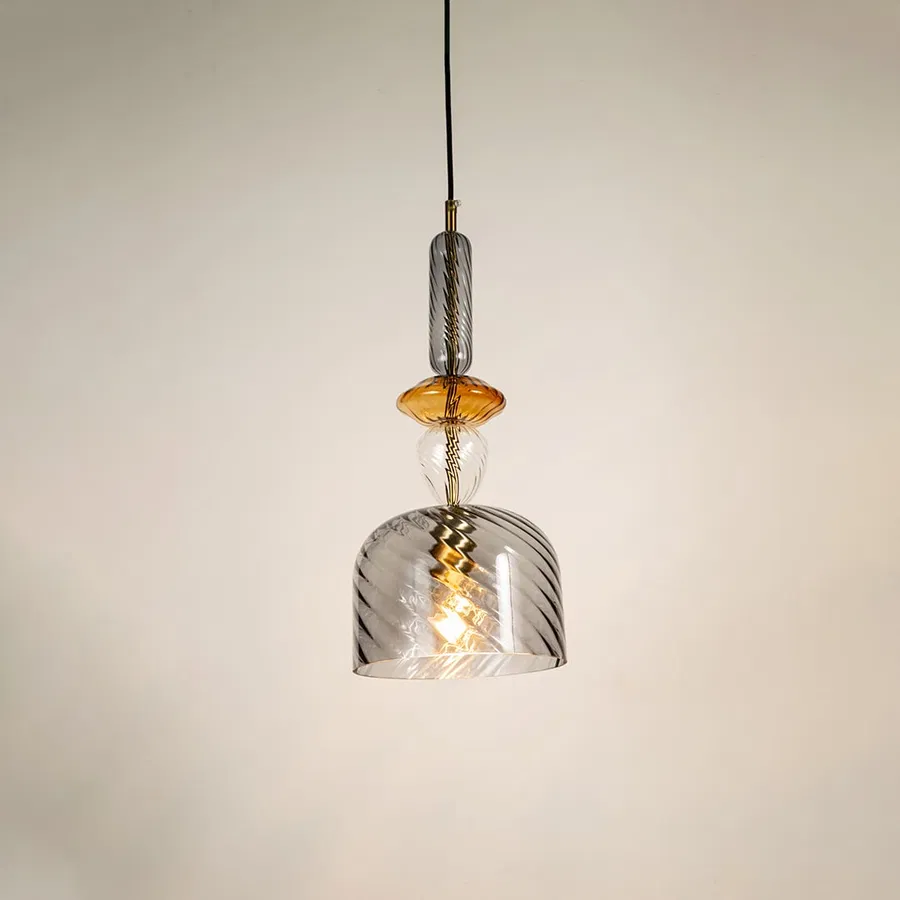 A grey and amber glass ceiling pendant light glows softly against a white background adding a modern ambience to any indoor space.