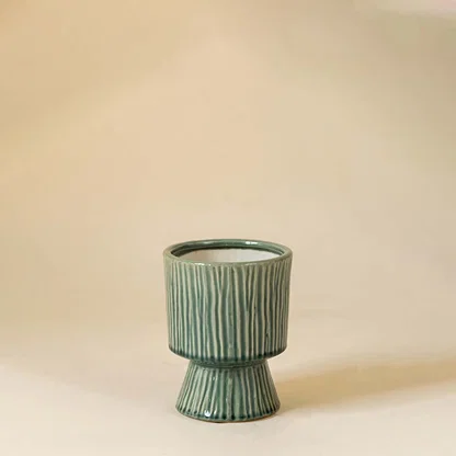 Green ceramic decorative vase with ribbed texture and sculptural base for tabletop styling and contemporary decor.