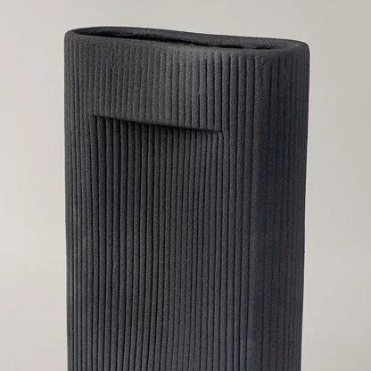 Closeup of tall black ceramic vase with vertical ribbed texture highlighting modern handcrafted detail for stylish home decor.