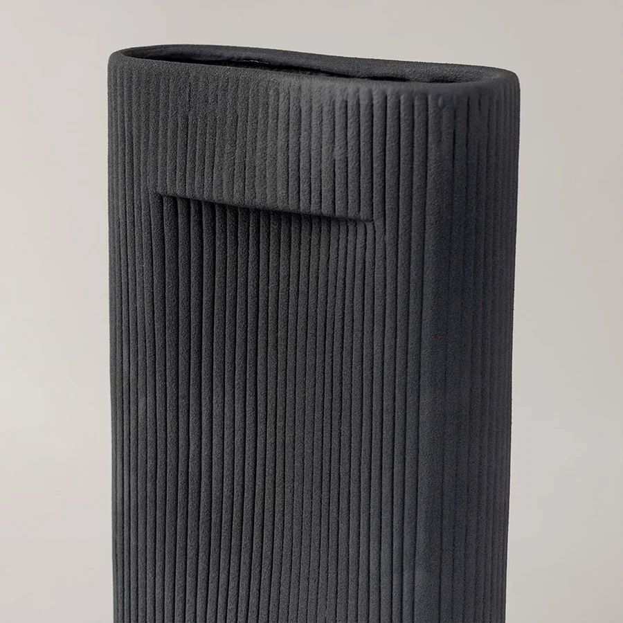 Closeup of tall black ceramic vase with vertical ribbed texture highlighting modern handcrafted detail for stylish home decor.