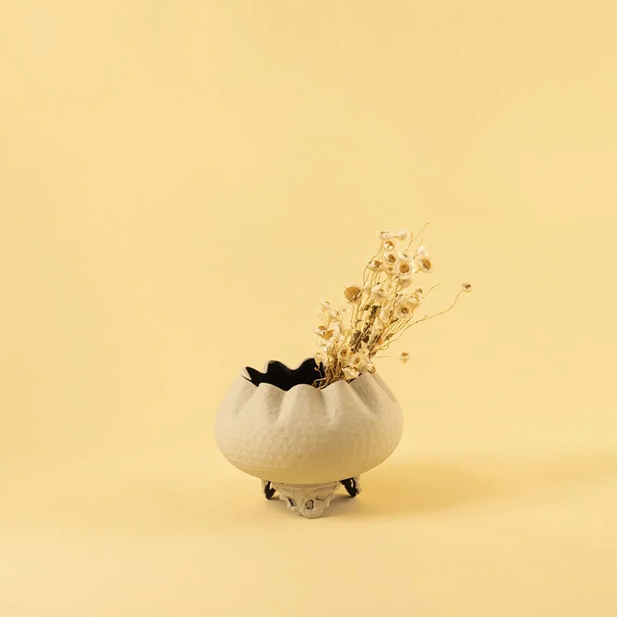 Cream metal scalloped bowl planter decor styled in a warm modern room adding a soft elegant accent to living room tables.