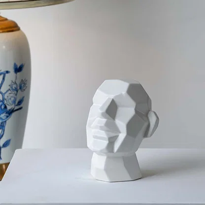 White geometric sculptures placed on wooden desk beside lamp and book enhancing elegant minimalist home setting.
