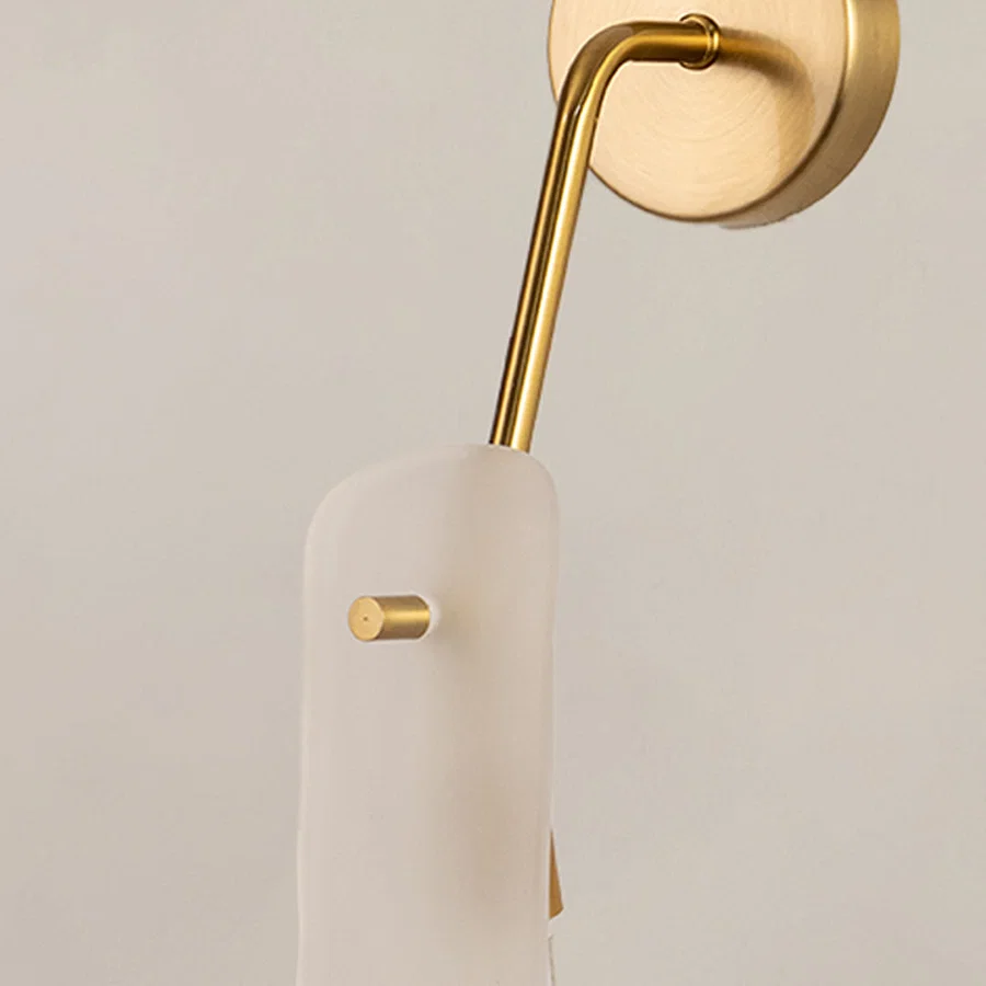 Closeup of gold metal wall light with frosted glass shade on white background ideal for bedroom hallway and modern interior decor.