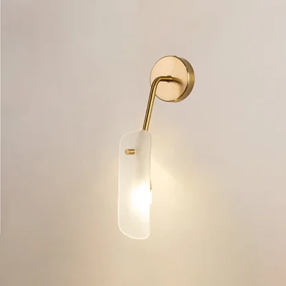 Gold wall light with frosted glass shade glowing softly against a clean white background for modern elegant home lighting decor.