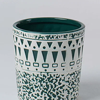 A close view of a ceramic planter with teal geometric and speckled patterns showing detailed craftsmanship and a smooth glossy interior finish.