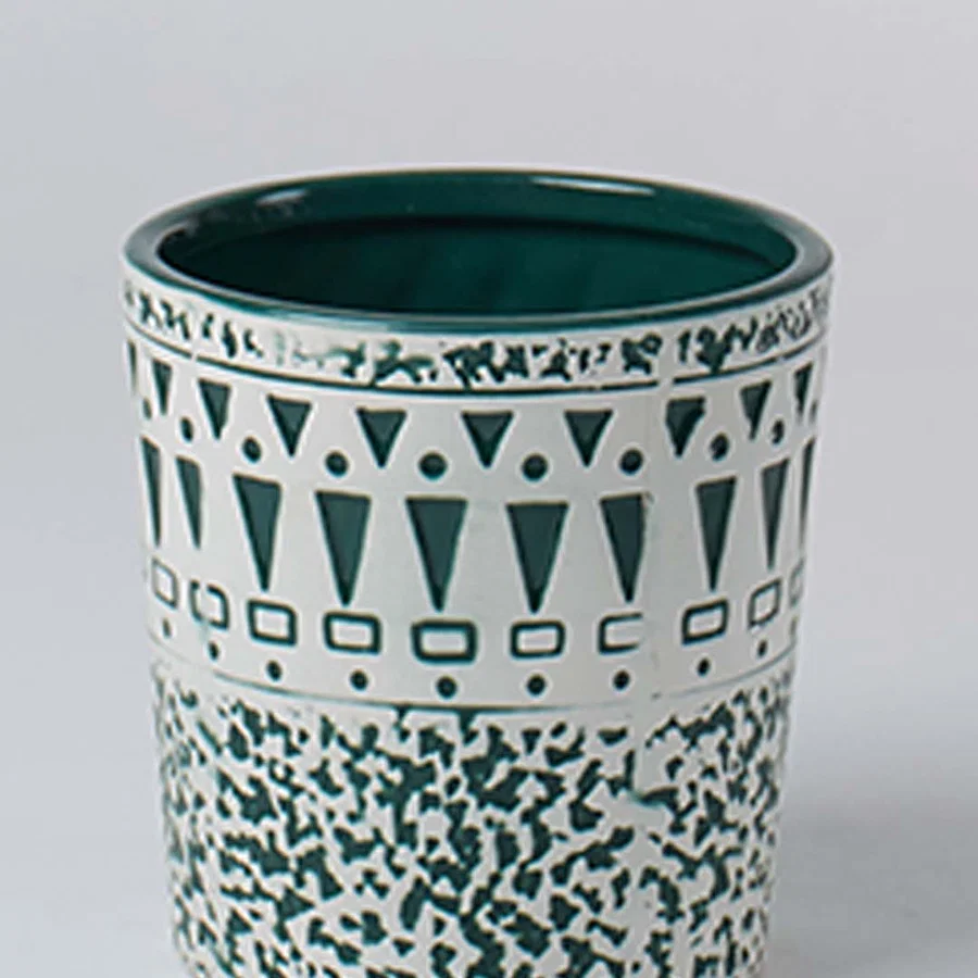 A close view of a ceramic planter with teal geometric and speckled patterns showing detailed craftsmanship and a smooth glossy interior finish.