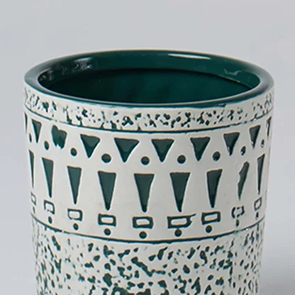 Closeup of ceramic planter showing teal geometric detailing and speckled texture for a stylish modern decor accent.
