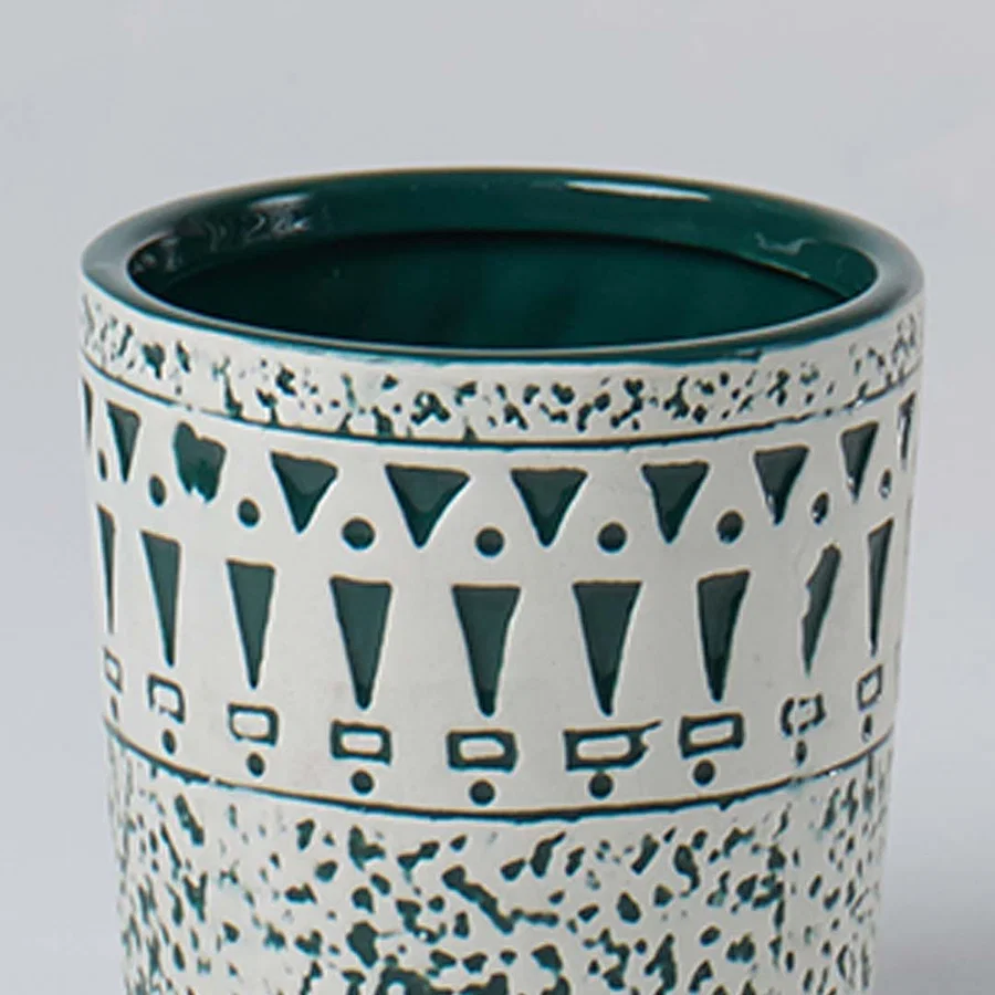 Closeup of ceramic planter showing teal geometric detailing and speckled texture for a stylish modern decor accent.