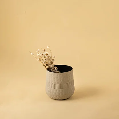 Small cream textured pot with black interior styled in a cozy modern space adding soft minimal decor to shelves and tables.