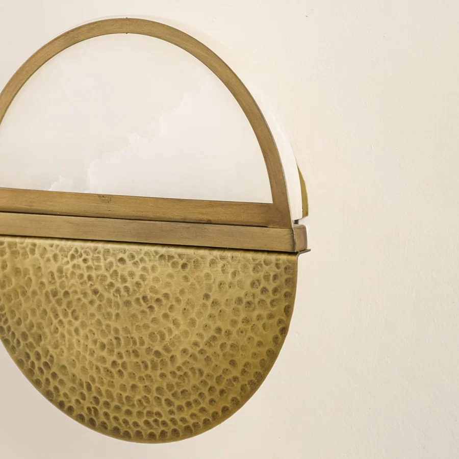 Closeup of textured gold metal wall light for elegant hallway and contemporary decor styling spaces.

