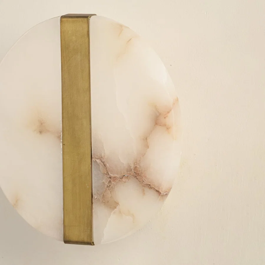 Closeup of marble and gold metal wall light for elegant hallway and luxury decor styling spaces.