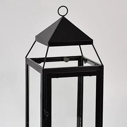 Closeup of black metal lantern with clear glass panels for modern tabletop decor styling use.