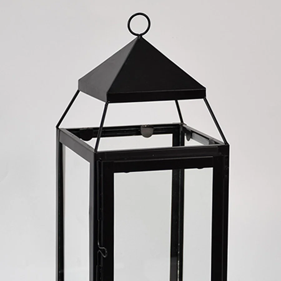 Closeup of black metal lantern with clear glass panels for modern tabletop decor styling use.