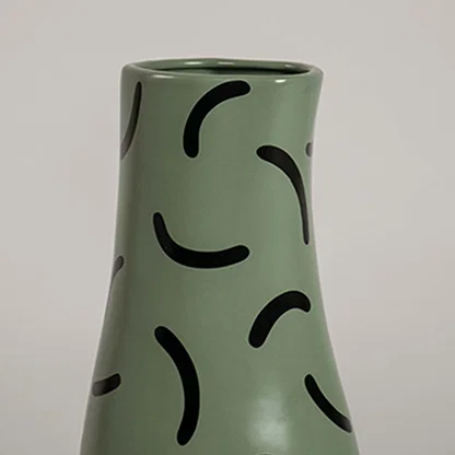 Closeup of green ceramic vase with bold black curved pattern showcasing its smooth finish and modern decorative detailing.