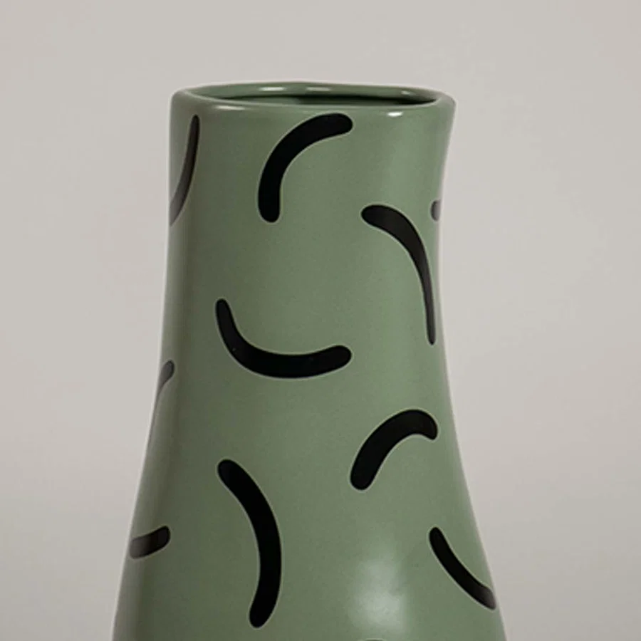 Closeup of green ceramic vase with bold black curved pattern showcasing its smooth finish and modern decorative detailing.