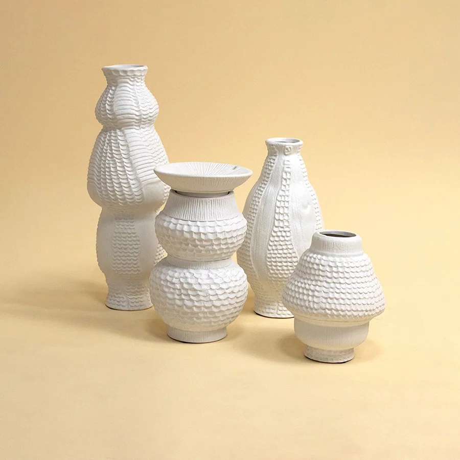 Set of white ceramic decorative vases with textured designs for contemporary shelf styling and elegant home decor.