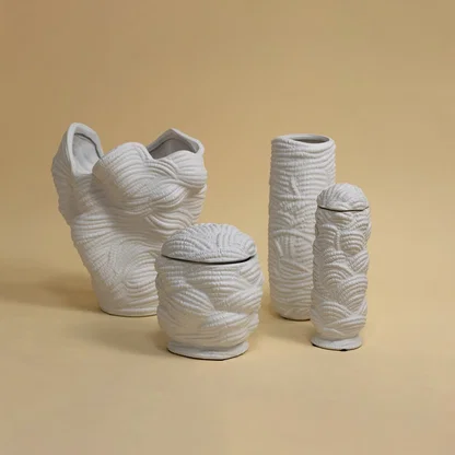 Set of white textured ceramic vases arranged together under soft lighting creating a modern art-inspired decorative ensemble.