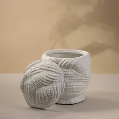 Contemporary white ceramic vase with detailed handcrafted design placed on a white background emphasizing its organic form.