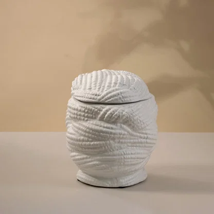Handcrafted white ceramic vase with a textured pattern glowing gently under light on white background showing artistic craftsmanship.