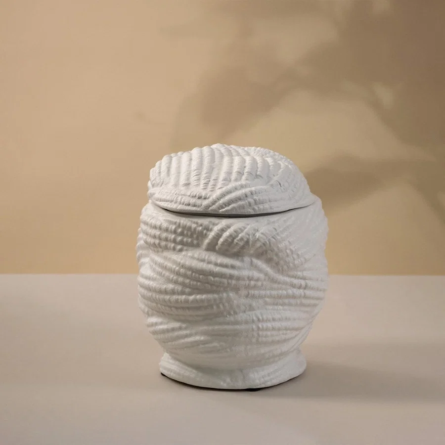 Handcrafted white ceramic vase with a textured pattern glowing gently under light on white background showing artistic craftsmanship.