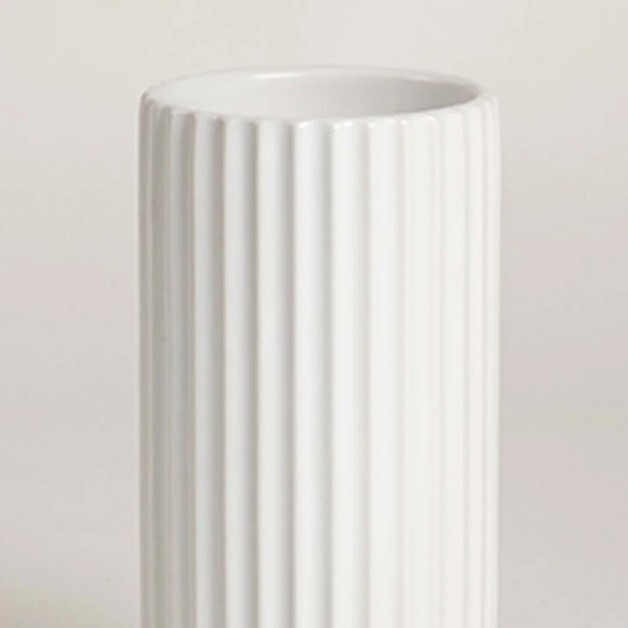 Closeup of white ceramic vase with vertical ribbed texture showcasing premium craftsmanship and modern decor styling.