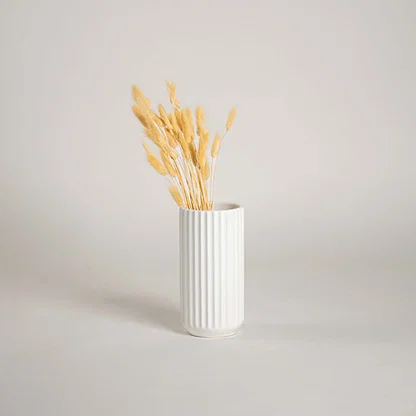 White ribbed ceramic vase placed in a soft minimal lifestyle scene adding a clean modern touch with its simple vertical textured design.