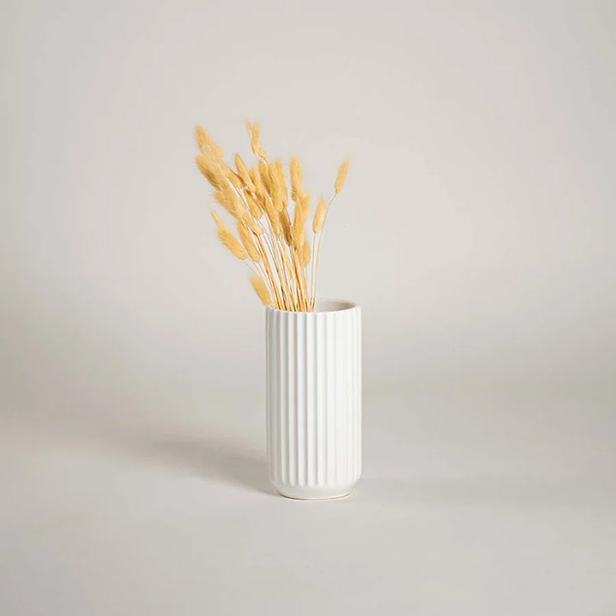White ribbed ceramic vase placed in a soft minimal lifestyle scene adding a clean modern touch with its simple vertical textured design.