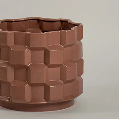 Closeup of brown ceramic planter showing its bold geometric textured pattern and glossy finish ideal for modern artistic home styling.